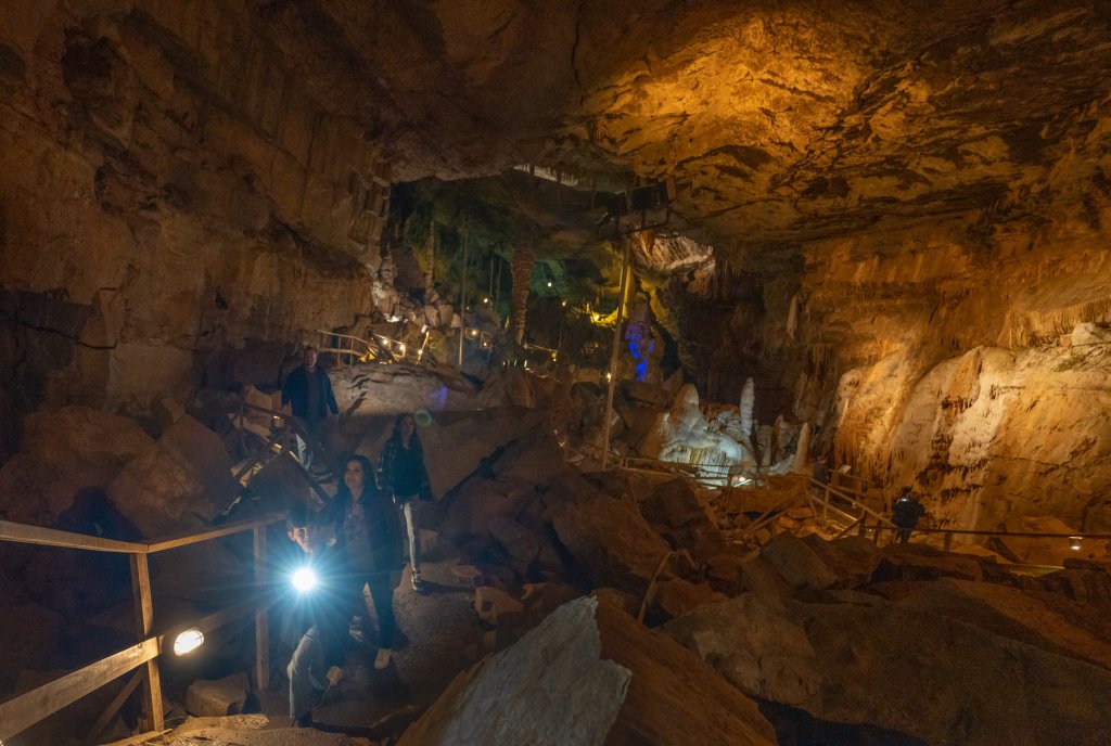 Visitors exploring Lost World Caverns in Greenbrier Valley, WV, surrounded by towering stalactites and rugged rock formations.